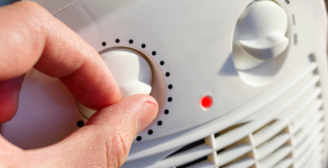Man's Hand Adjusts The Temperature Of The Electric Fan Heater At