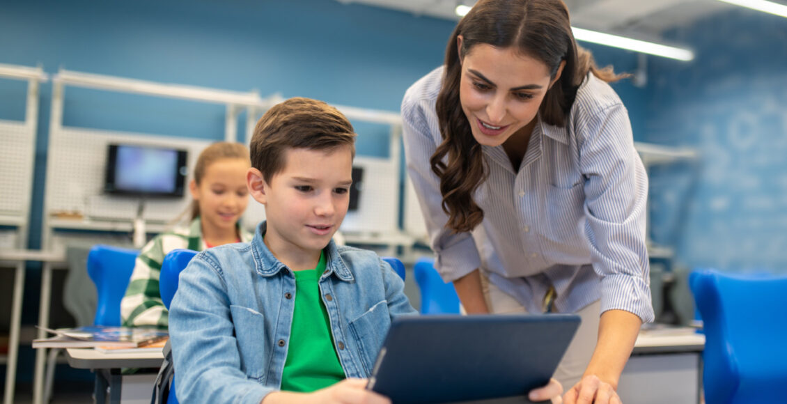 Woman Looking Into Tablet Of Student Boy