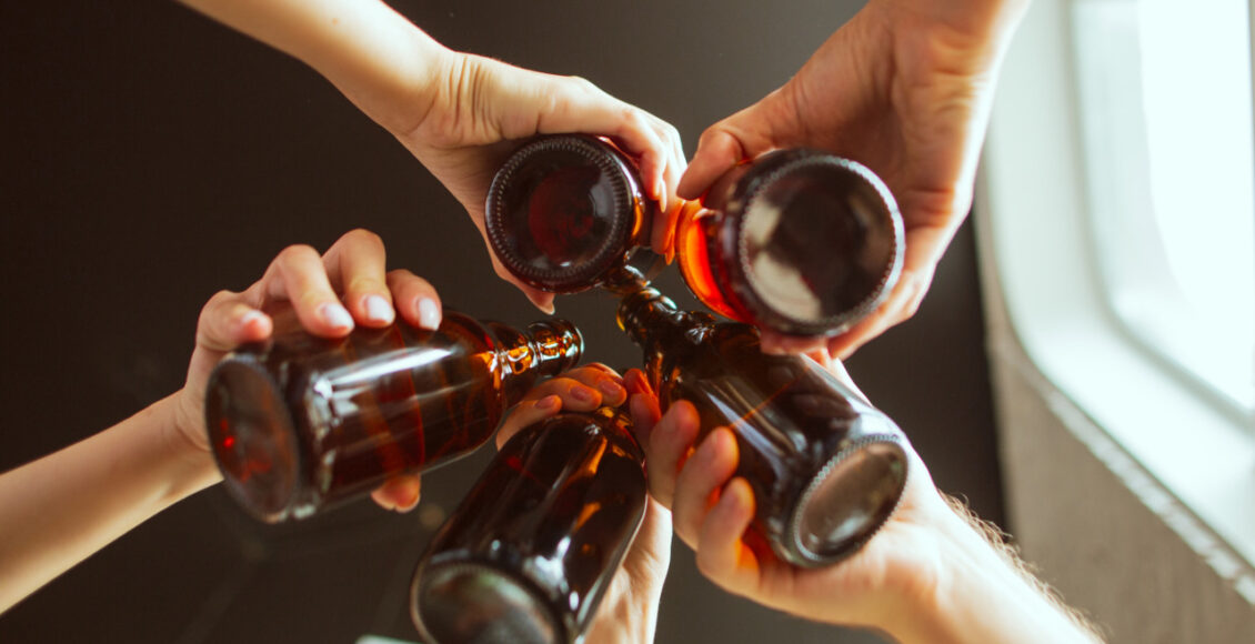 Young Group Of Friends Drinking Beer, Having Fun, Laughting And Celebrating Together. Close Up Clinking Beer Glasses