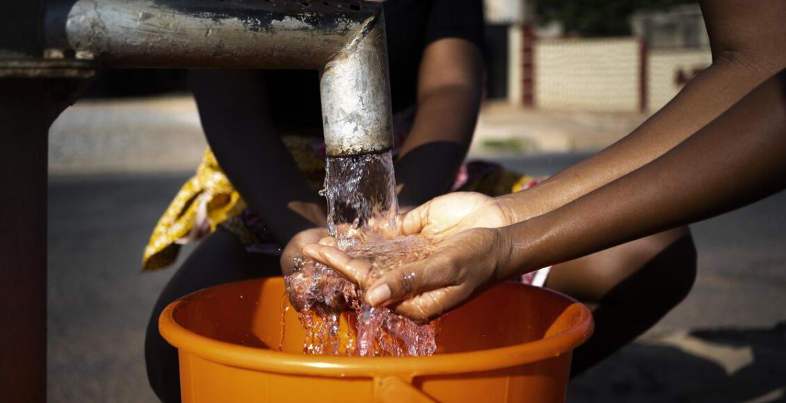 African Woman Pouring Water Recipient Outdoors