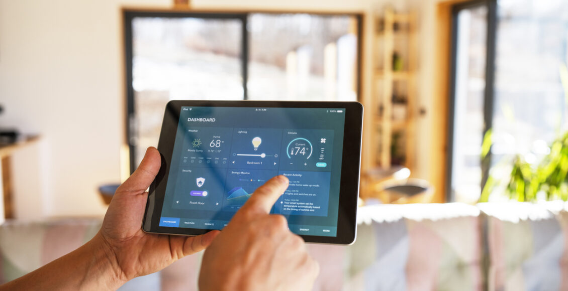 Man Using Tablet With Smart Home Control Functions At Home.