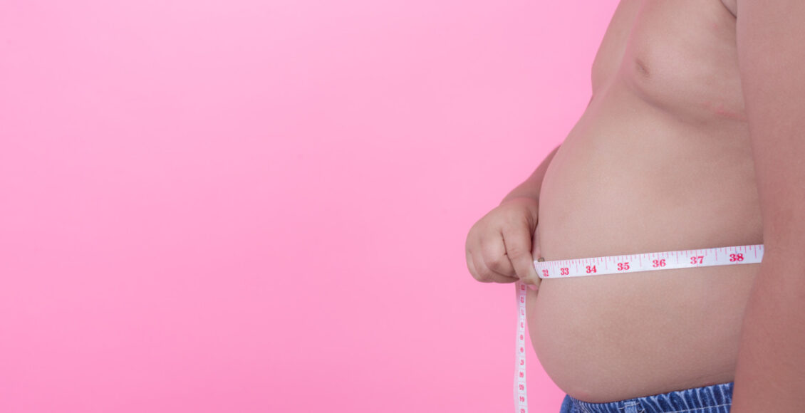 Obese Boy Who Is Overweight On A Pink Background.