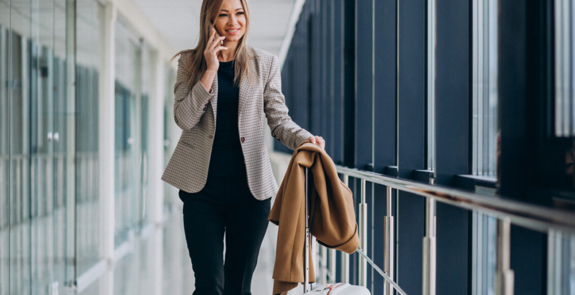Business Woman In Terminal With Travel Bag Talking On Phone