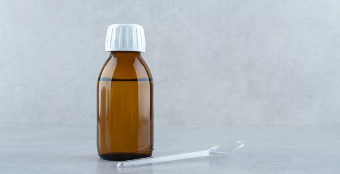A Jar Of Medicine Drink With Plastic Spoon