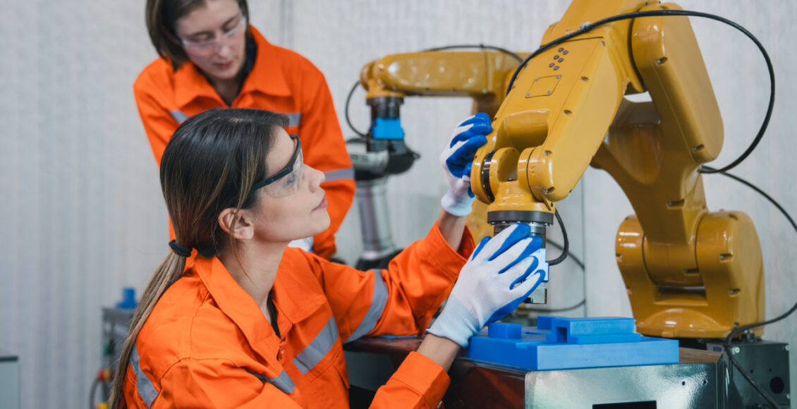 Student Engineer Assembling Robotic Arm With Computer In Technology Workshop. Service Engineer Holding Robot Controller And Checking Robotic Arm Welding Hardware.